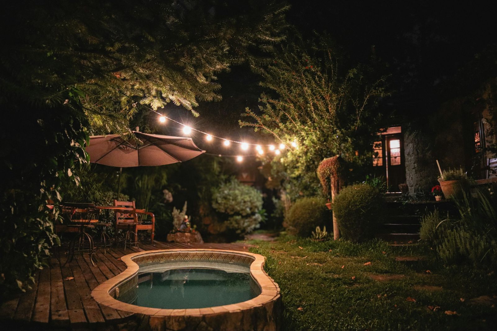 Garden at night lit by string lights, lanterns and warm outdoor lighting